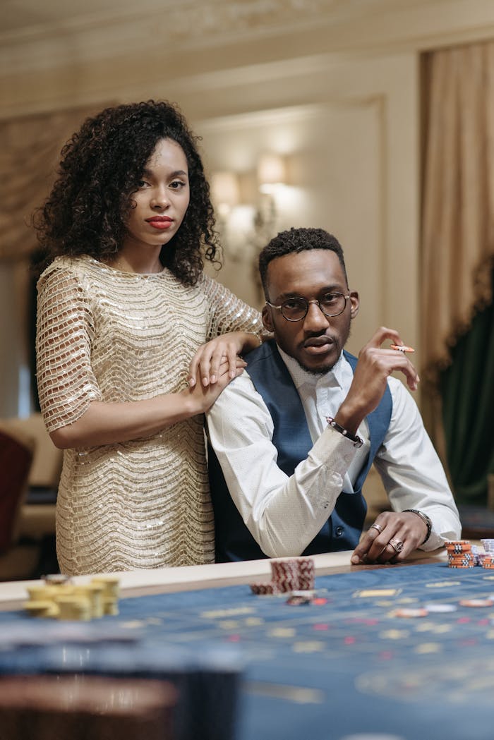 Sophisticated couple sitting with poker chips at a luxurious casino table indoors.